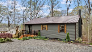 Een huis met twee verdiepingen, een metalen dak, houten luiken en een veranda met een balustrade.