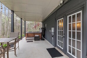 A covered outdoor area with a hot tub, seating, and a door with glass panels. - Waterfront Home - Hot Tub, Dock, Fire Pit, Boat (Lake Norman of Catawba)