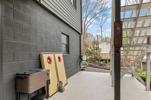 Een betonnen terras met twee houten deuren, een kleine tafel en een tas.