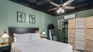 Een keurig opgemaakte slaapkamer met een groot bed, nachtlampjes, een plafondventilator en een kledingkast.