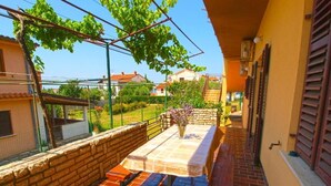 A patio with a table and benches, a pergola with vines, and a view of neighboring houses. - Cozy Apartment in Peroj With Terrace (Vodnjan)
