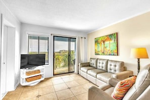 Un salon avec un canapé, une télévision et un balcon offrant une vue agréable.