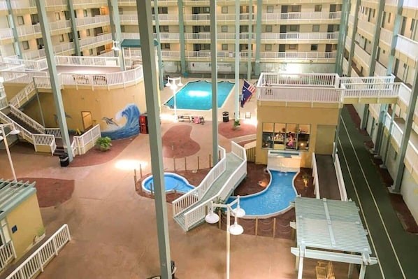 Área interna de piscina com vários níveis, incluindo piscina central, várias varandas e um espaço de recreação infantil.