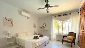 A bedroom with a bed, bedside tables, a chair, a ceiling fan, and a window with curtains. - Impressive villa with private pool & sea views on a finca (AN)