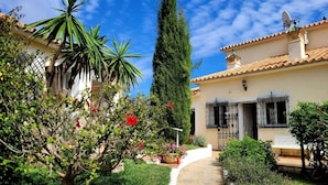 A courtyard with a stone pathway, a tall tree, and a building with a tiled roof and a satellite dish. - Impressive villa with private pool & sea views on a finca (AN)