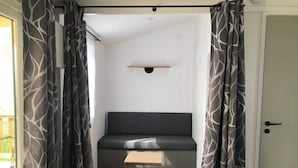 Una habitación con un sofá de color oscuro, una pequeña mesa de madera y cortinas estampadas.