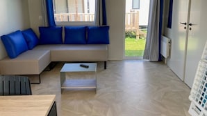 Un salon moderne avec un canapé, une table basse et une porte-fenêtre coulissante donnant sur un balcon.