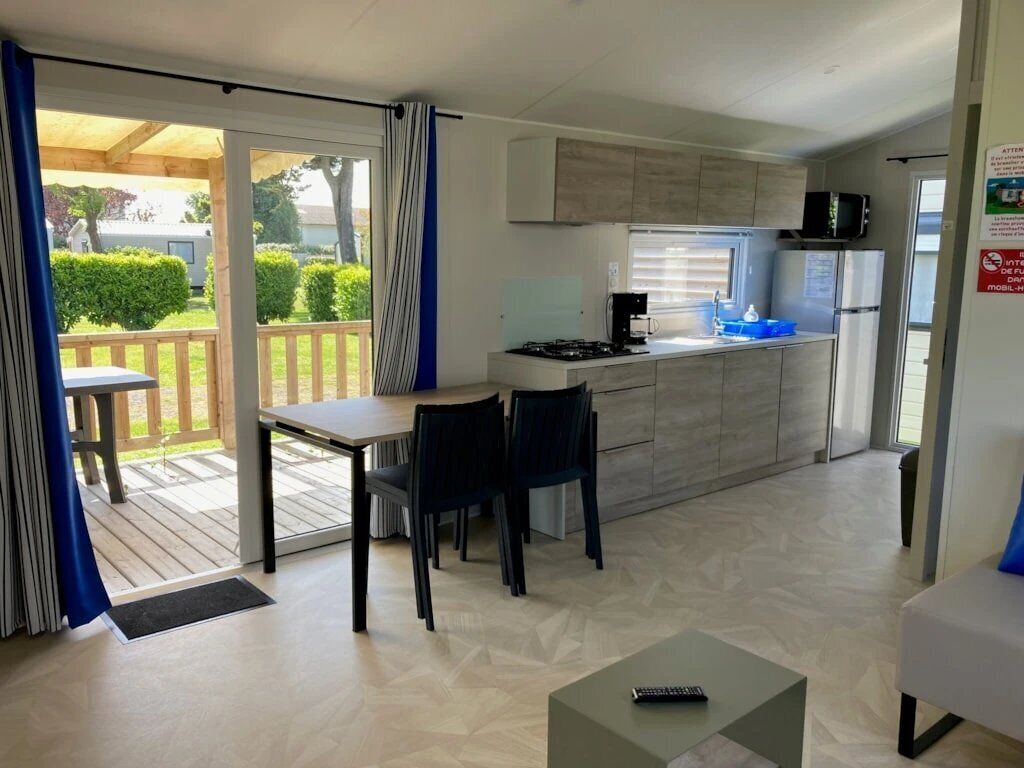 A modern kitchen with a dining area, a small table, and a view of the outdoors.