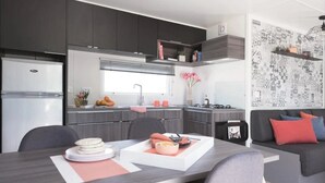 Una cocina moderna con armarios oscuros, una mesa de comedor con platos y un sofá con cojines.
