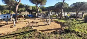 A campsite with outdoor exercise equipment, trees, and mobile homes.