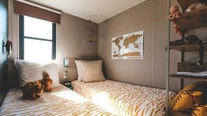A bedroom with two beds, a world map on the wall, and a shelf with stuffed animals.