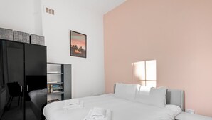 Une chambre à coucher moderne, comprenant un lit, des tables de chevet, une armoire et un bureau.