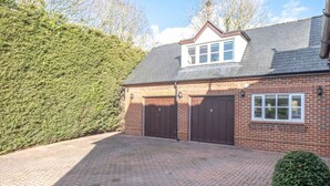 A two-story brick house with a garage, a small window, and a sloped roof. - Cosy loft apartment near Oxford - Pass the Keys (Abingdon)