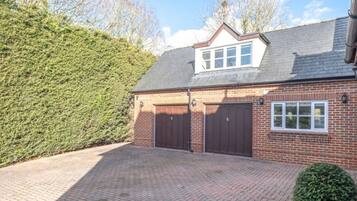 A two-story brick house with a garage, a small window, and a sloped roof.