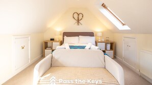 A bedroom with a bed, bedside tables, a nightstand, a wall decoration, and a skylight. - Cosy loft apartment near Oxford - Pass the Keys (Abingdon)
