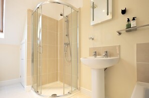 A modern bathroom with a glass-enclosed shower, a pedestal sink, and a mirror above the sink.