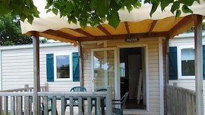 En overdækket veranda med træterrasse, et lille bord og to stole.