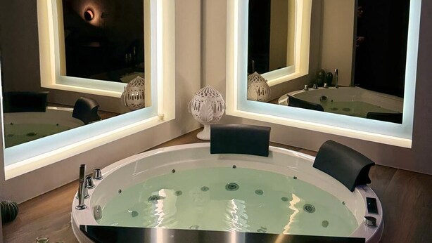 A modern bathroom with a freestanding bathtub, two large mirrors, and a vanity with a sink. - Via del Mare Apulia B&B  Spa Suite (Rutigliano)