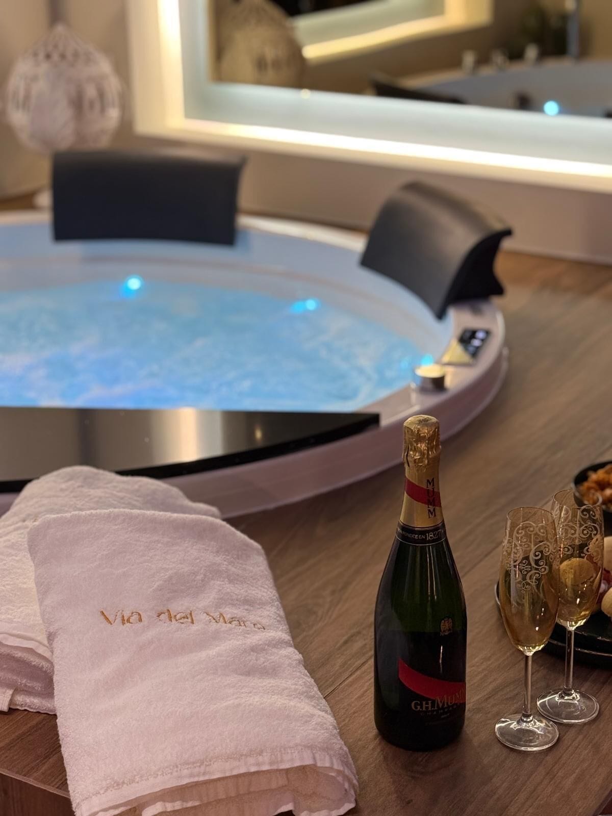Un espace de détente avec un bain à remous, une bouteille de champagne et deux verres.