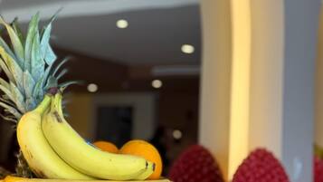 Una exposición de frutas con plátanos, naranjas y una piña en un cuenco texturizado.