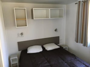 Un dormitorio con cama, dos mesitas de noche, un cabecero y dos armarios empotrados.