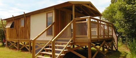 A wooden cabin with a covered porch and a staircase leading to a deck.