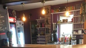 Un espace bar avec un comptoir, des tabourets et des étagères remplies de bouteilles.