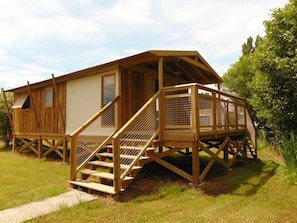 Een houten chalet met een overdekte veranda en een trap naar een terras.