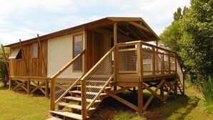 A wooden cabin with a covered porch and a staircase leading to a deck. - ZEcamping 3 étoiles piscine couverte locatif TV LV 43m2 (Avrillé)