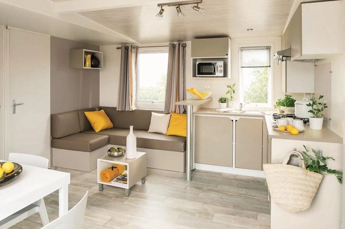 A compact living space with a sofa, a small dining table, a kitchenette, and a window with curtains.