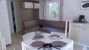 Une petite cuisine équipée avec une table à manger, un canapé et une fenêtre avec des rideaux.