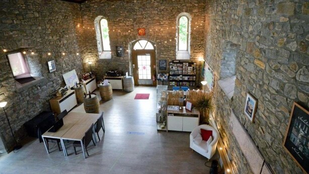 Interior rústico de pedra com área de jantar, bar e estantes de livros.