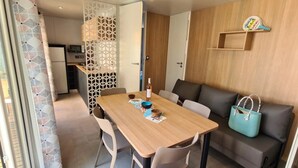 A modern living room with a wooden dining table, a sofa, and a teal handbag. - ZEcamping 3* dog friendly piscine dans le parc régional du Verdon (Valensole)