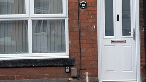 A residential building with a white front door, a number plate, and a window with a curtain. - Prime Location 5 Bed En-suite 6 Bathrooms in Derby Sleeps up to 10 People. (Derby)