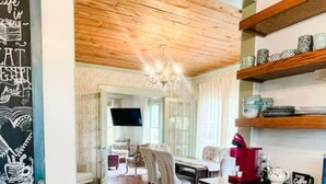 A modern kitchen with wooden cabinets, a coffee machine, and a dining area with a chandelier.
