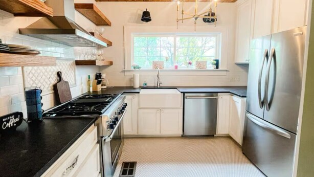 A modern kitchen with white cabinets, a stainless steel refrigerator, and a window above the sink.