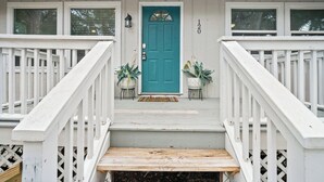 A house with a teal front door, white railings, and a small porch with two potted plants. - Frippin Graytful, Golf Cart Included, Pet Friendly - 120 Sea Otter (Fripp Island)