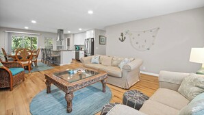 A spacious living area with a dining table, sofa, and a kitchen in the background. - Frippin Graytful, Golf Cart Included, Pet Friendly - 120 Sea Otter (Fripp Island)