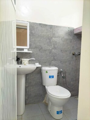 A compact bathroom with a toilet, sink, and shower. - HOTEL 7DAYS (Dakhla)