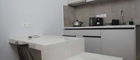 Une cuisine moderne avec des armoires blanches, un plan de travail en marbre et un four encastré.