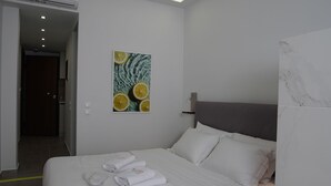 Et moderne hotelværelse med en stor seng, et sengebord, en vægmonteret aircondition og et billede af citrusfrugter.