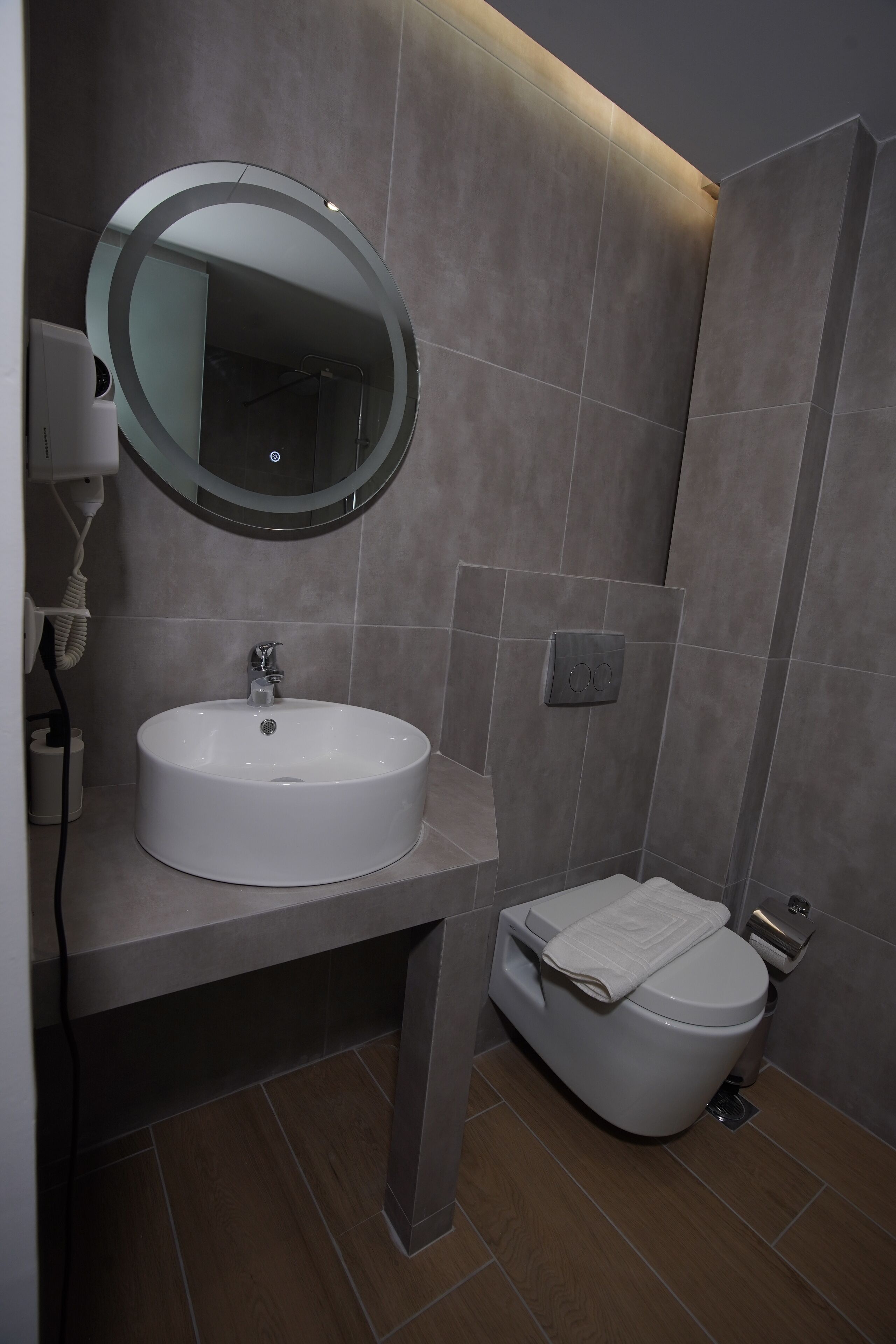 A modern bathroom with a round mirror, a sink, and a toilet.
