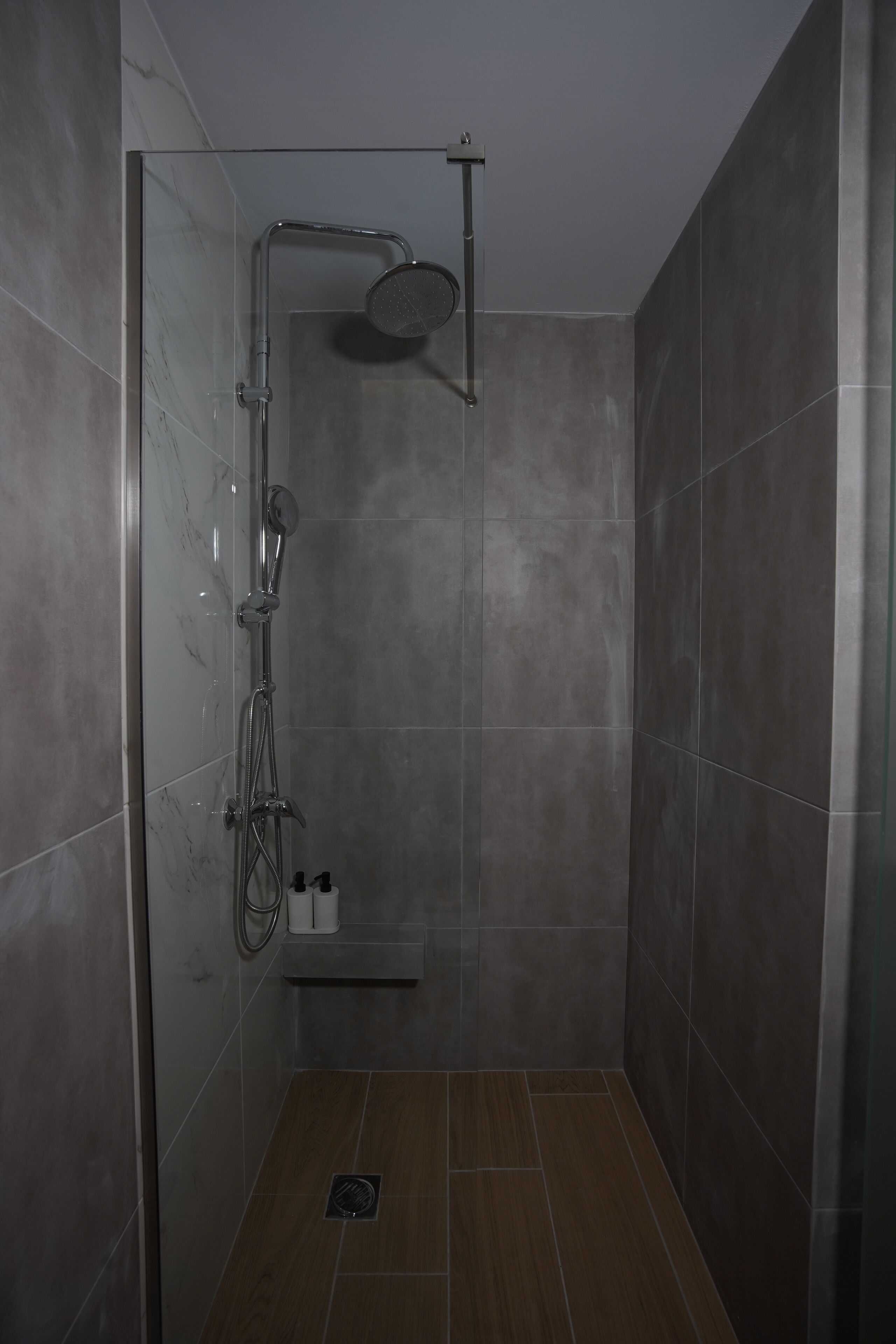 A shower with a glass door, a handheld showerhead, and a wall-mounted faucet.