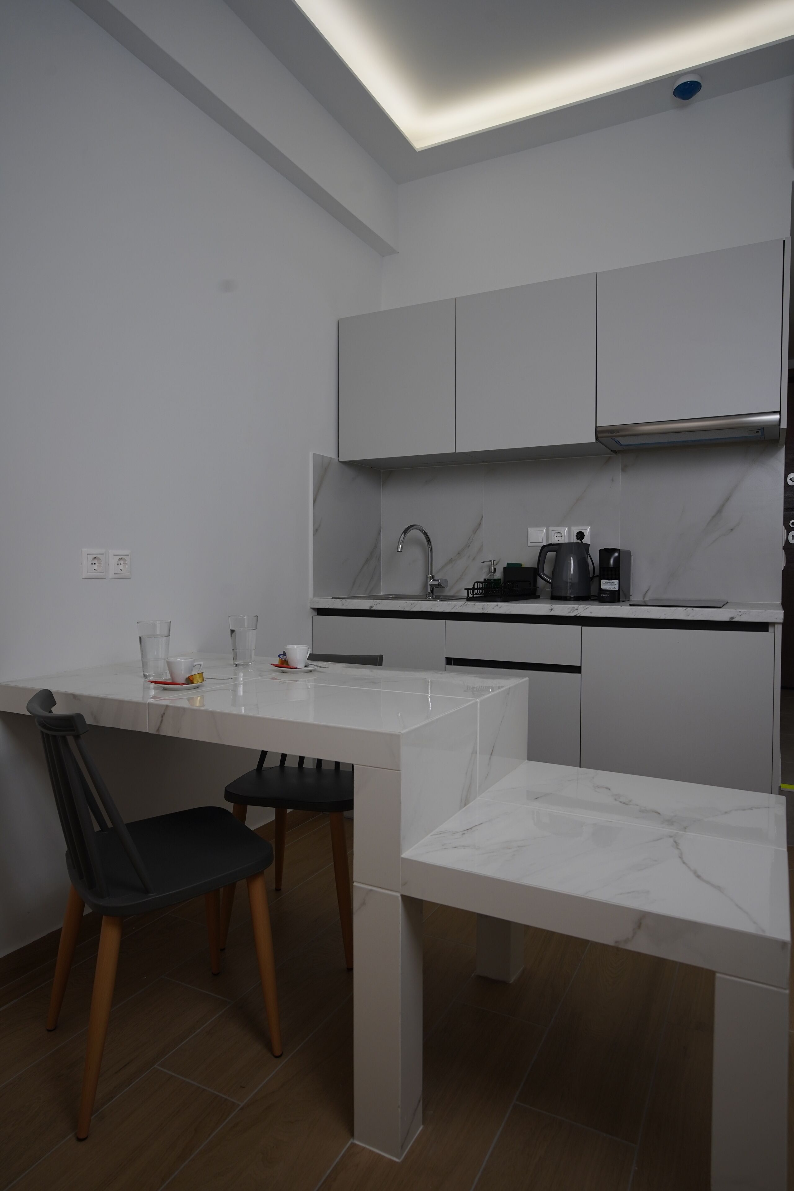 Una cocina moderna con armarios blancos, encimera de mármol y una silla negra.