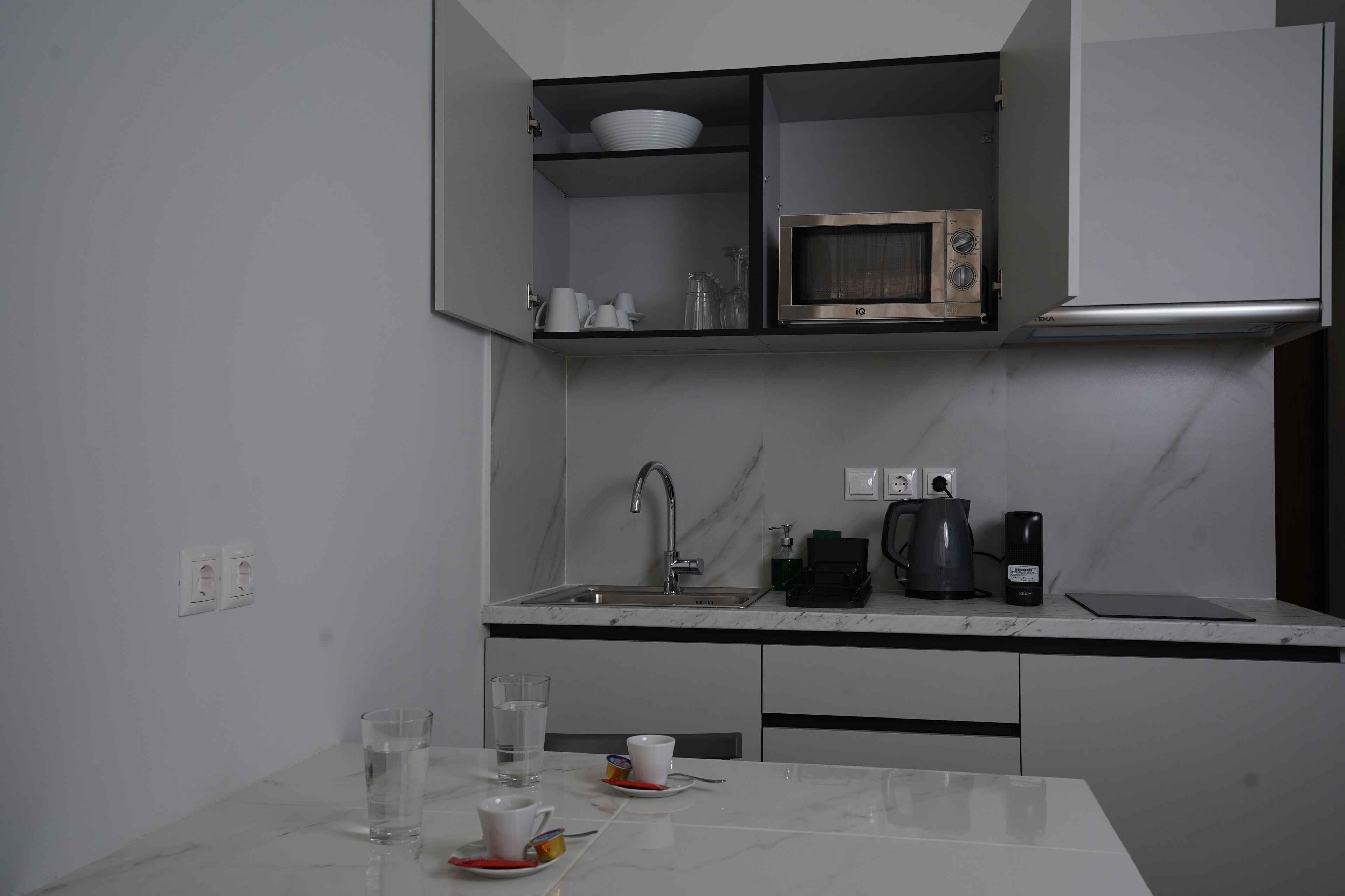 A compact kitchen with a built-in microwave, a sink, and a coffee maker.