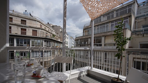 En balkon med et bord, stole og en potteplante.