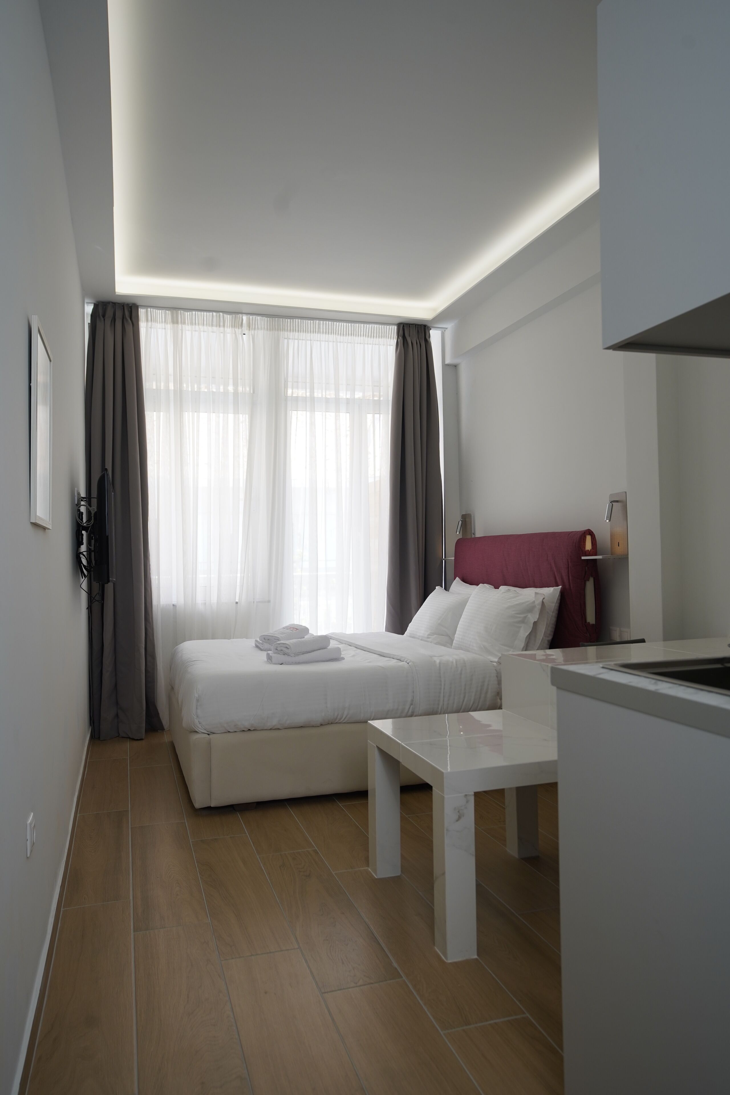 A modern hotel room with a bed, a small table, and a desk.