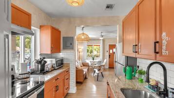 A kitchen with a dining area, featuring a microwave, sink, and cabinets.