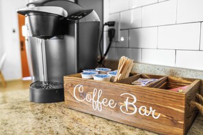 A wooden coffee bar with a coffee maker and coffee pods.