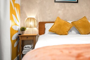 A neatly made bed with two pillows, a bedside lamp, a small plant, and a folded towel on a wooden nightstand. - Miami+3BR+8 Guest +Near Cruise Port + Calle 8 +Brickell+South Beach+Free Parking (Miami)